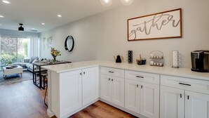 A modern kitchen with white cabinets, a central island, and a dining area with a sofa and coffee table. - Camelback Casa | Old Town Scottsdale | New Remodel (Scottsdale)
