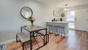 A modern kitchen with a dining area, featuring a wooden table, bar stools, and a round mirror. - Camelback Casa | Old Town Scottsdale | New Remodel (Scottsdale)