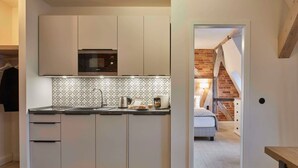 A modern kitchen with white cabinets, a patterned backsplash, and a built-in microwave.