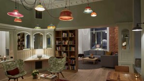 A spacious living room with a wooden coffee table, two armchairs, a bookshelf, and a fireplace. - Studio - VIA's Appartements am Postplatz (Görlitz)