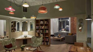 A spacious living room with a wooden coffee table, two armchairs, a bookshelf, and a fireplace. - Superior apartment - VIA's Appartements am Postplatz (Görlitz)