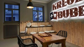 A cozy room with a wooden table and chairs, a chessboard, and a wall with the text "KREUZ BUBE". - Superior apartment - VIA's Appartements am Postplatz (Görlitz)