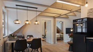 Una cocina moderna con vigas de madera, un comedor con sillas negras y un refrigerador negro.