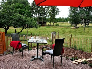An outdoor patio with a table and chairs, surrounded by a wooden fence and greenery. - Schlafkoje Kleine Wolke - Schäfchenwolke Apartment auf dem Bauernhof (Worpswede)