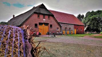 Ein Backsteinhaus mit rotem Dach, einer großen Holztür und einem Fahrrad davor.