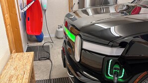 A car charging in a garage with a wooden bench, a red container, and a gas cylinder. - ❄Ski in/out❄- Best Group Rental on Schweitzer-  Book now for holidays! (Sandpoint)