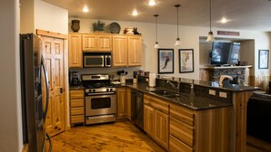 A modern kitchen with wooden cabinets, stainless steel appliances, granite countertops, and pendant lighting. - ❄Ski in/out❄- Best Group Rental on Schweitzer-  Book now for holidays! (Sandpoint)