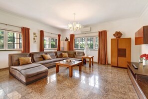 A spacious living room with a sectional sofa, a coffee table, and a chandelier.
