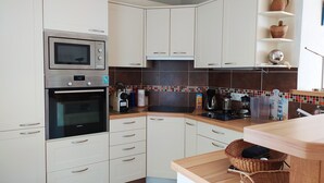 Una cocina moderna con armarios blancos, electrodomésticos de acero inoxidable, un backsplash de azulejos y una encimera de madera.