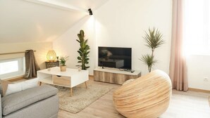 A modern living room with a sofa, a coffee table, a TV, and decorative plants.