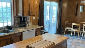 Une cuisine avec des meubles en bois, un plan de travail en granit, une machine à café et un coin repas comprenant une table et des chaises.