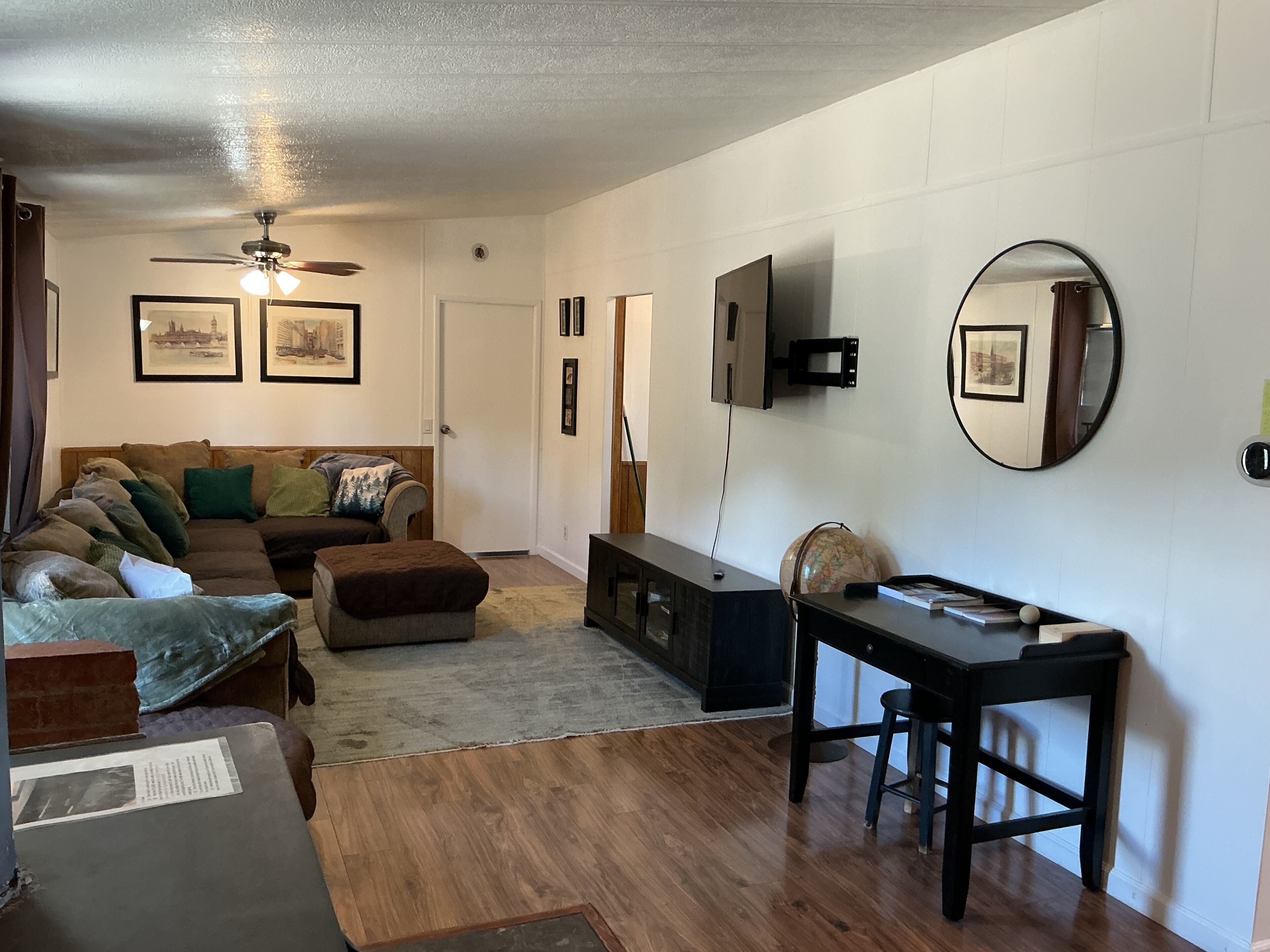 A living room with a sofa, ottoman, coffee table, TV, and a globe.
