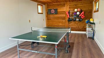 A ping pong table in a room with wooden walls and a ceiling fan.