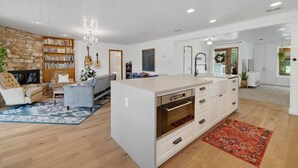 A spacious living area with a large white island, a stone wall bookshelf, and a fireplace.