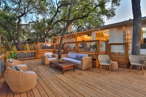 Une terrasse extérieure aménagée avec des meubles en osier, une table en bois et une cheminée en pierre.