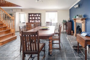 Enjoy meals in this dining area with a large table and six chairs, a fireplace, and a staircase leading to an upper level.