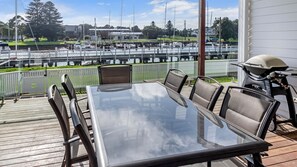 Un coin repas avec une table et des chaises en verre, donnant sur une marina où sont amarrés des bateaux.