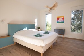 Quarto com cama, mesa de cabeceira, janela e uma obra de arte na parede.