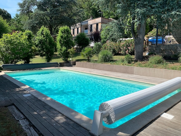 Uma piscina retangular com água azul cristalina, rodeada por um deck de madeira.