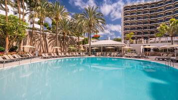 Una piscina al aire libre, sombrillas, sillones reclinables de piscina