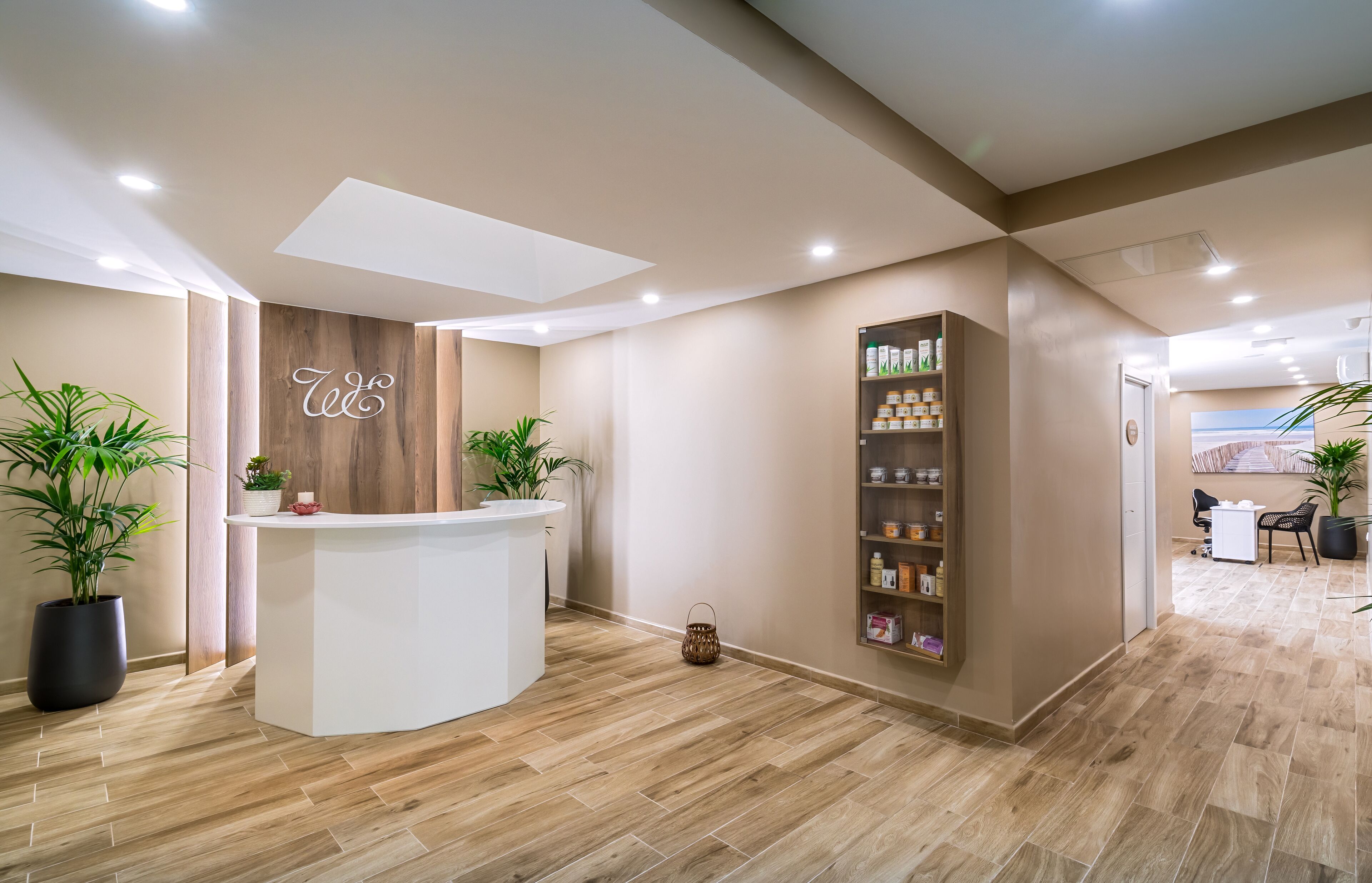A reception area with a wooden reception desk, potted plants, and a shelf with products.