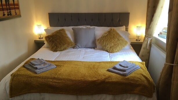 A neatly made bed with a tufted headboard, two pillows, and a blanket. - Lazy Nest - Sleeps 4, Parking, Garden & Hammocks (Oakham)
