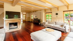 A spacious living room with hardwood floors, a fireplace, a sofa, and a television.