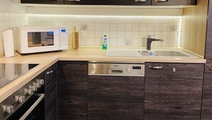 Een moderne keuken met donkere houtkasten, een wit aanrecht, een magnetron, een spoelbak en een vaatwasser.
