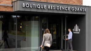 Boutique Residence Gdańsk -hotellin sisäänkäynti, jossa on lasijulkisivu ja musta markiisi, johon on kirjoitettu hotellin nimi.