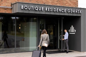 The entrance to Boutique Residence Gdańsk with a glass facade and a black awning displaying the name.