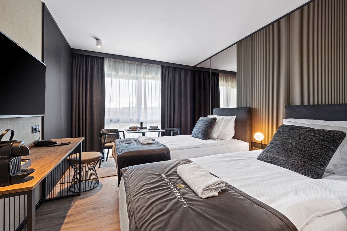 Een moderne hotelkamer met twee bedden, een bureau en een zithoek.