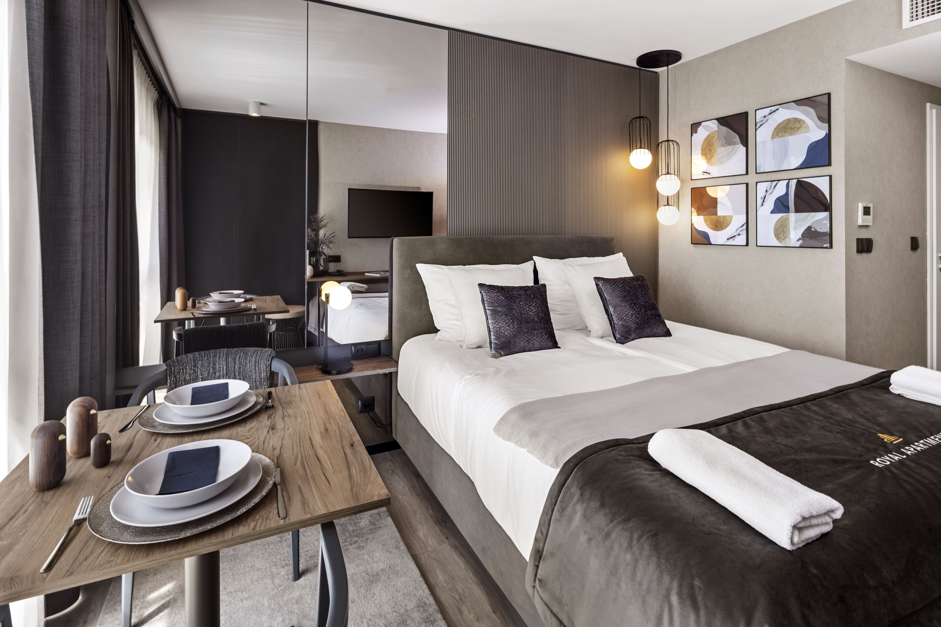 A hotel room with a bed, bedside table, and a desk with a chair.