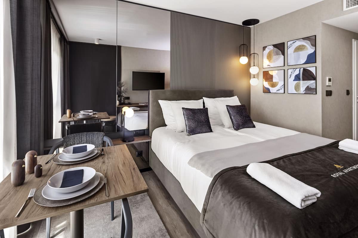 A hotel room with a bed, bedside table, and a desk with a chair.