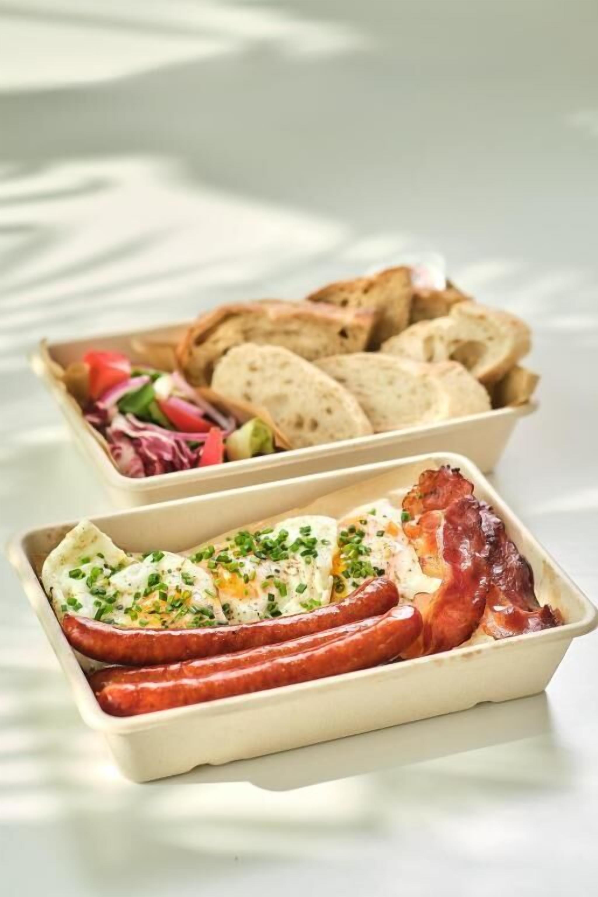A tray with sliced bread and a dish containing eggs and bacon.