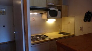 A compact kitchen with a stove, microwave, and sink. - 2-room apartment, 4 people, Méribel center, close to shops & slopes (Méribel)