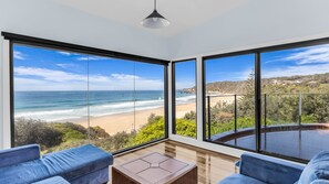 A room with large windows offering a view of the beach and ocean.