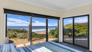 A bedroom with a large sliding glass door leading to a balcony with a beach view. - Bermi Bliss - Dickinson Avenue 7 (Bermagui)