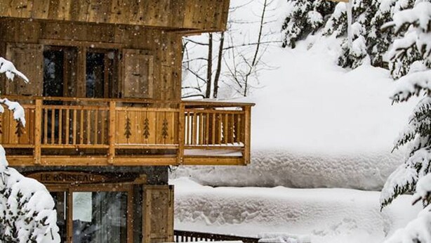 A wooden cabin with a balcony, surrounded by snow-covered trees. - Family Apartment in Peaceful Area, Close to Slopes (Méribel)