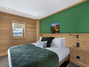 Um quarto com uma cama, janela, parede verde e um quadro.