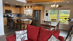 A modern kitchen with wooden cabinets, stainless steel appliances, and a dining area with a red sofa and patterned cushions.