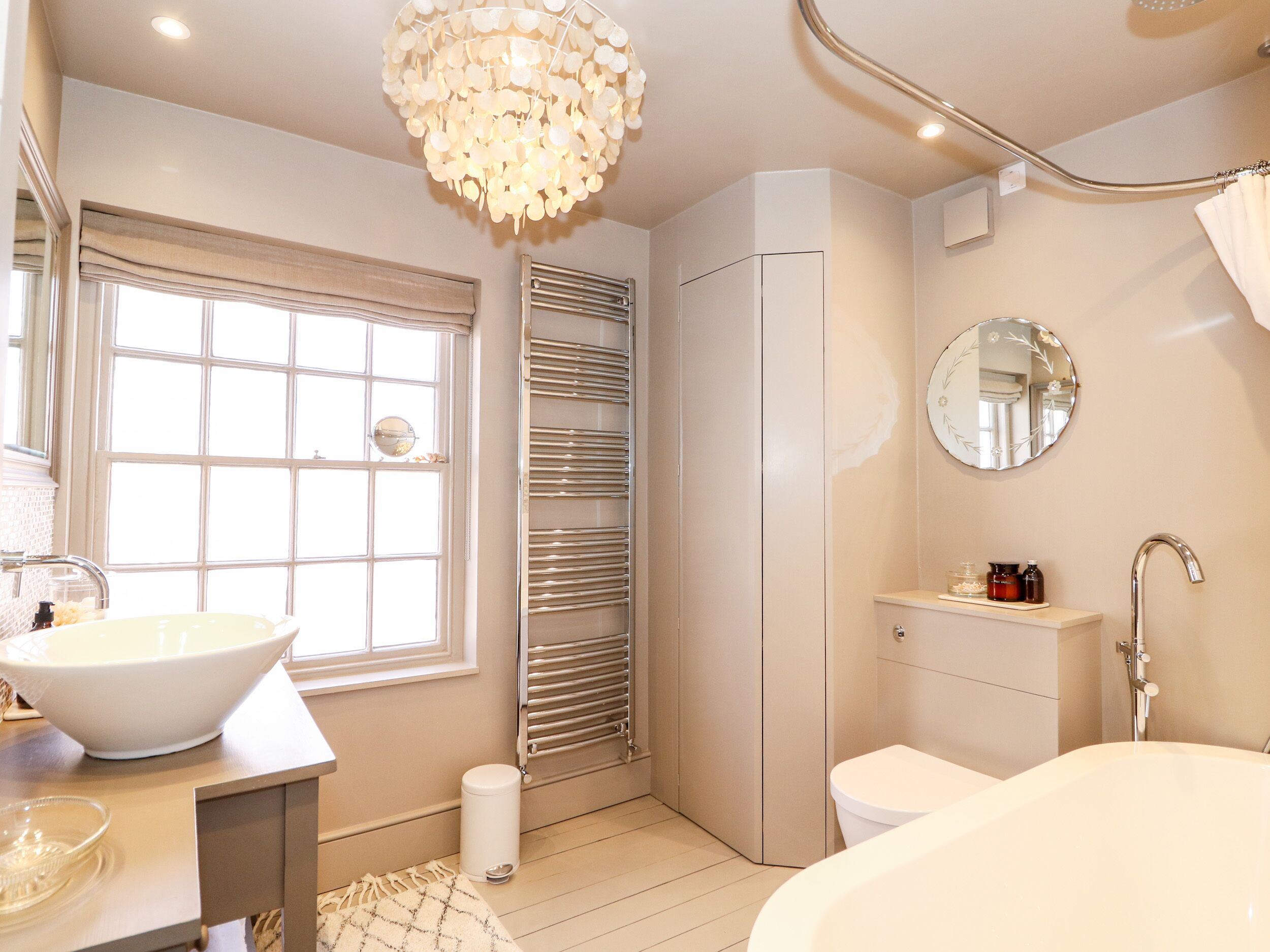 Un baño moderno con un ventanal grande, un lavabo blanco, una bañera y un inodoro.