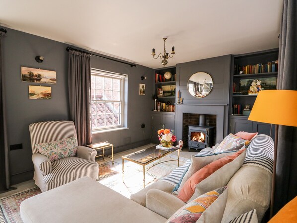 Una sala de estar con sofá, sillón, chimenea y estanterías.