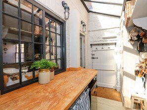 Una cocina con encimera de madera, ventana con marcos negros y puerta blanca.