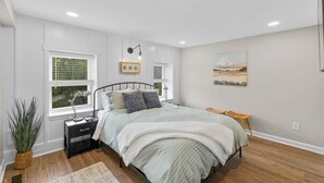 Una camera da letto con un letto, un comodino, una lampada e un quadro appeso al muro.
