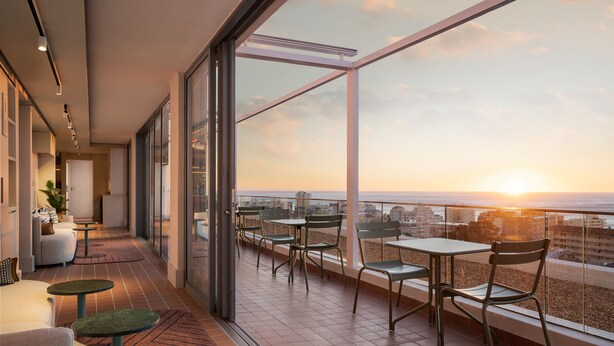 A balcony with a view of the sunset over the ocean, furnished with chairs and tables. - Home Suite Hotels Sea Point (Cape Town)