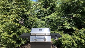 A portable grill with a digital display, control knobs, and a fuel canister attached.
