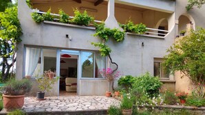 Una casa moderna con entrada empedrada en piedra, puertas de vidrio amplias y un patio cubierto.