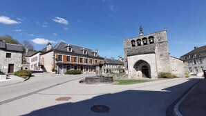 Un edificio de piedra histórico con un patio central, una fuente y una estatua en la parte superior.