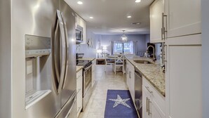 A modern kitchen with stainless steel appliances, a dining area with a chandelier, and a view of the outdoors. - 256 Stoney Creek - Walk to Harbour Town to watch the Pros at the Heritage! (Hilton Head Island)