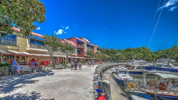 A marina with boats docked, a pedestrian walkway, and buildings with outdoor seating. - 256 Stoney Creek - Walk to Harbour Town to watch the Pros at the Heritage! (Hilton Head Island)